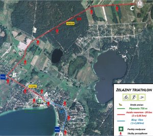 Na zdjęciu uwidoczniona została trasa zawodów triatlonowych „Żelazny Bieg”. Z lewej strony widoczne jest Jezioro Białe wokół którego zaznaczone zostały zabudowania. Z prawej strony od znaku Policja zaznaczone zostały postacie człowieka w kolorze czerwonym wyznaczające trasę zawodów.