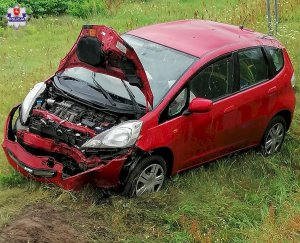 Samochód m-ki Honda Jazz koloru czerwonego, które uczestniczyło w zdarzeniu drogowym. Samochód uszkodzony po tym jak dachował.